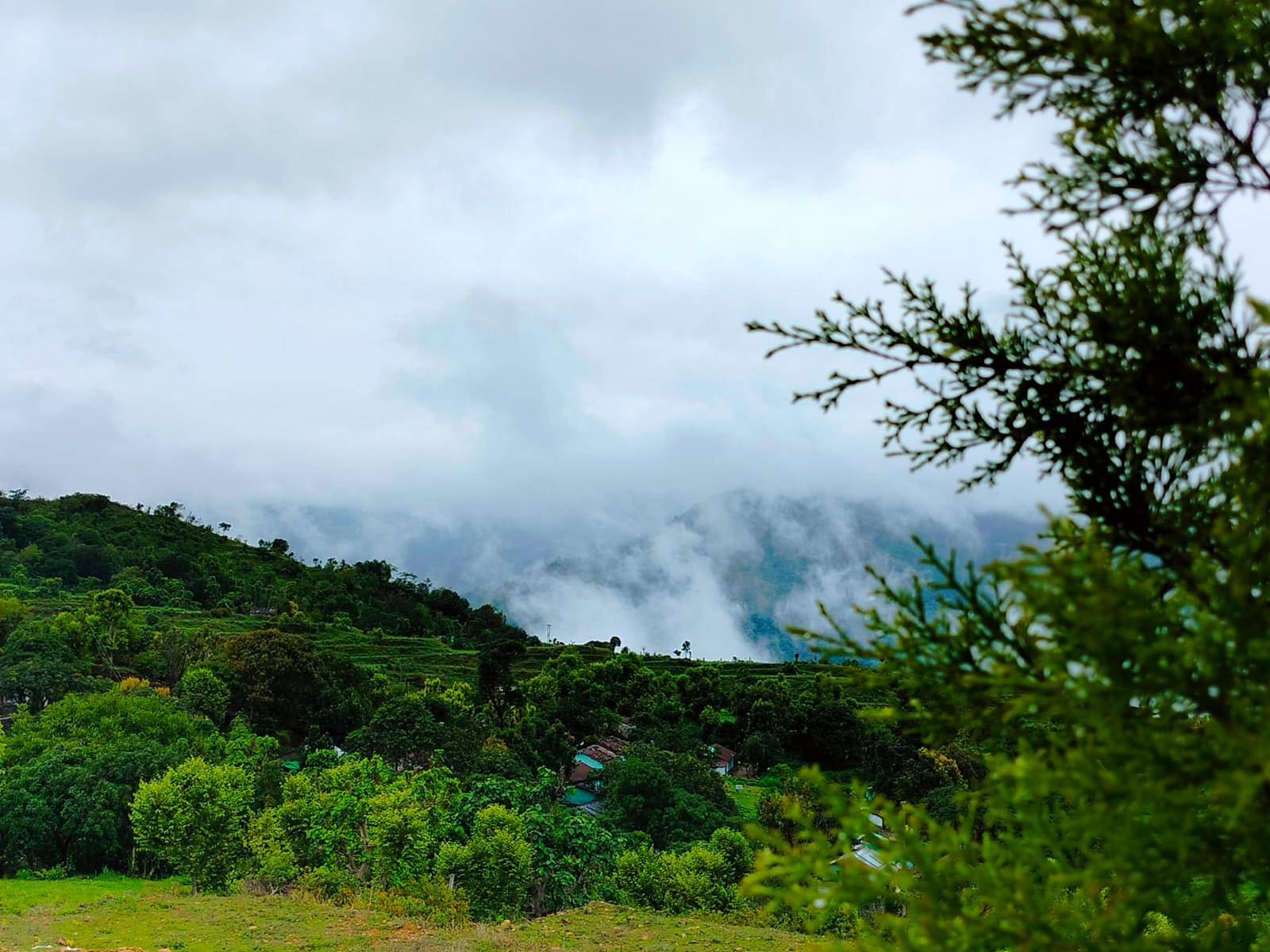 Mist rolling across a green hillside village below the resort
