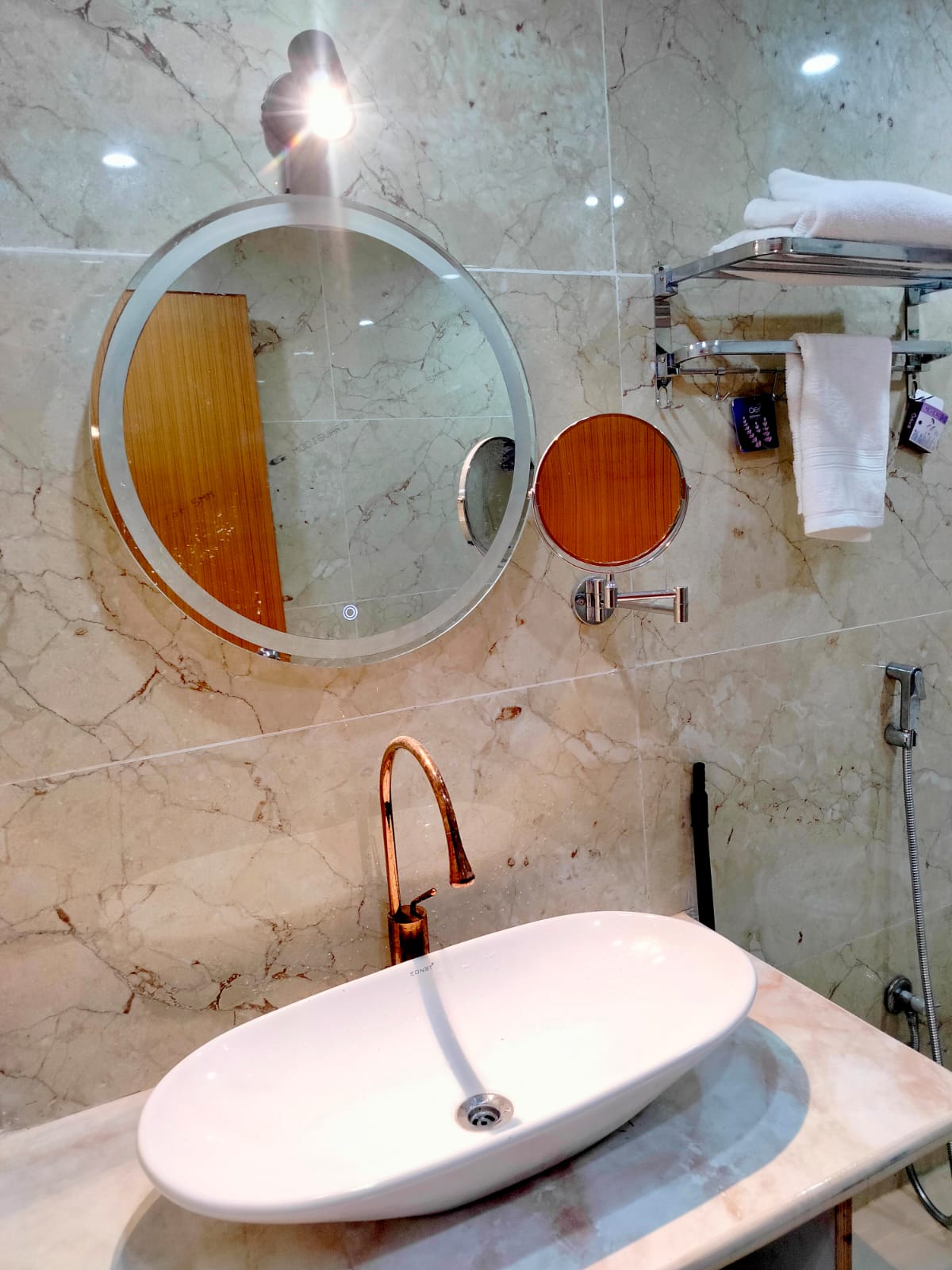 Marble bathroom vanity with backlit round mirror and vessel basin